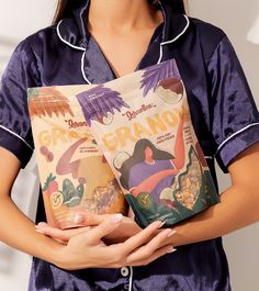 a woman holding two bags of granola in her hands, both with the same label on them