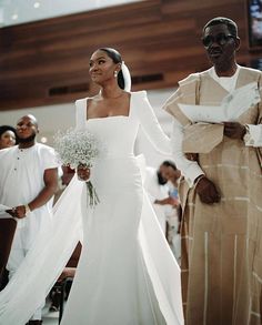 a bride and groom walking down the aisle at their wedding ceremony, with other people in the background