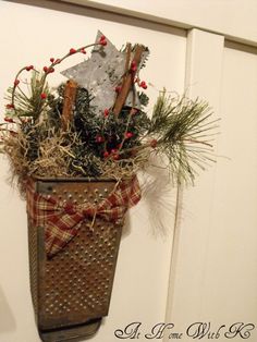 a christmas decoration hanging from the side of a door with pine cones and berries in it