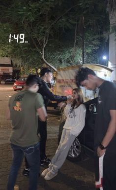 a group of people standing next to each other in front of a food truck at night