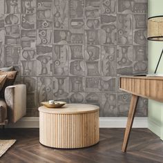 a living room with a couch, coffee table and wallpaper on the walls in grey tones