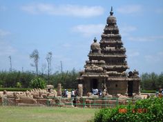 people are standing in front of an elaborately carved stone structure at the entrance to a park