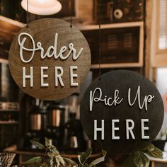 two wooden signs hanging from the side of a wall next to a coffee shop counter