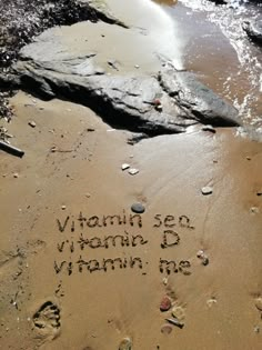 the words vitamin sea vitamin d vitamin me written in sand on beach with rocks and water