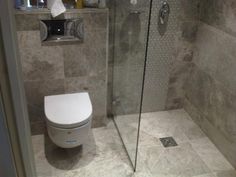 a bathroom with a glass shower door and white toilet in the corner next to it