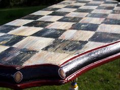 an old chess board sitting on top of a wooden table in the middle of a grassy area