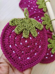 a crocheted strawberry with leaves on it sitting next to a piece of yarn