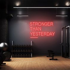 a gym with neon signs and dumbs in front of the wall that says,'stronger than yesterday '