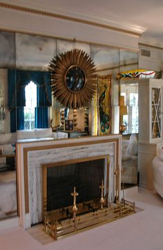 a living room filled with furniture and a fire place in front of a mirror wall