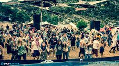 a large group of people standing around each other in front of a tent and trees