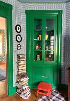 a green china cabinet with books stacked on top