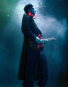 a man with blue makeup playing guitar on stage