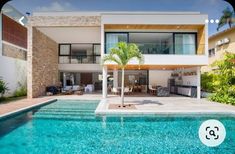 a large pool in front of a modern house with an outdoor kitchen and dining area