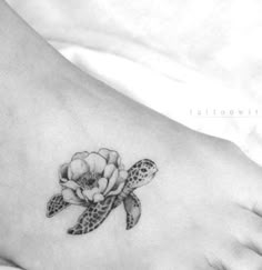 a small tattoo on the foot of a woman with a turtle and flower in it