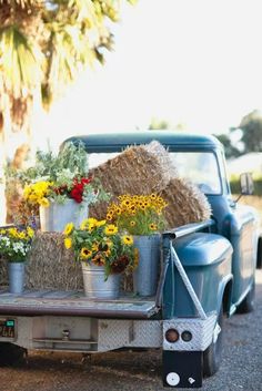 an old truck with flowers and hay in the back