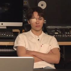 a young man sitting in front of a laptop computer with his arms crossed and looking at the screen