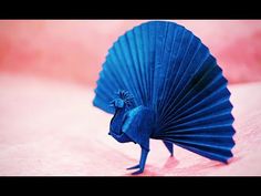 a small blue object sitting on top of a pink surface with its legs spread out