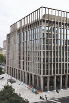 an office building with many windows and people walking on the sidewalk