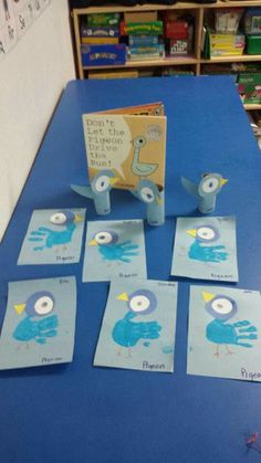 several cards with pictures of birds on them sitting on a blue table in front of bookshelves