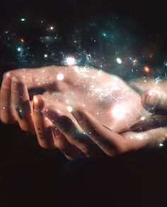 two hands holding each other in the middle of space with stars and dust all around them