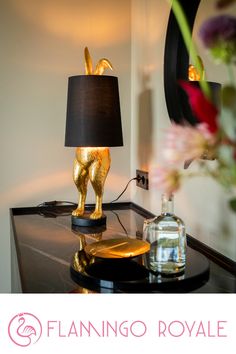 a lamp that is sitting on top of a table next to a vase with flowers