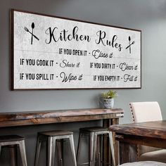 a kitchen rules sign hanging on the wall above a dining room table and bar stools