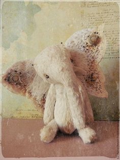 a white stuffed animal sitting on top of a wooden table next to an old piece of paper