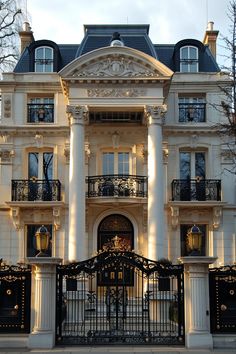 an ornate building with wrought iron gates and balconies on the top floor, surrounded by trees