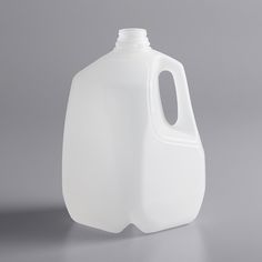 a gallon of white liquid sitting on top of a gray table next to a black object