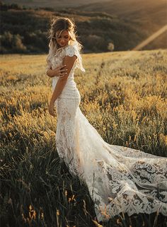 a woman standing in a field with mountains in the background