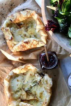 two pies sitting on top of wax paper next to a salad and dipping sauce