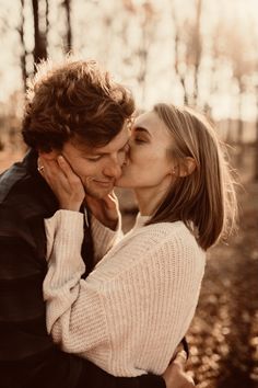 a man and woman kissing in the woods