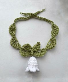 a crocheted necklace with a white bell on it