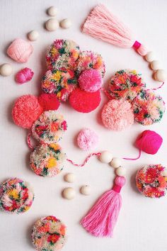 several different types of pom poms on a white surface with beads and tassels