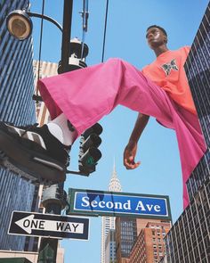 a man hanging off the side of a traffic light next to a one way sign