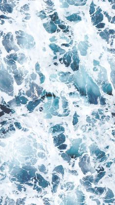 an aerial view of the ocean with blue and white waves