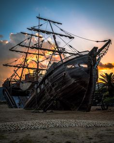 an old ship sitting on top of a sandy beach