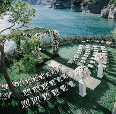 an outdoor ceremony setup with white flowers and greenery on the lawn by the water