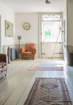 a living room filled with furniture and a large rug on top of a hard wood floor