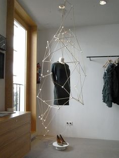 a room that has some clothes hanging on the wall and lights in the air above it