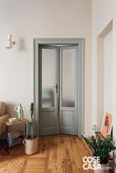 an empty room with two doors and potted plants on the floor next to it