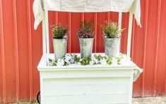 three potted plants are sitting on top of a white bench with an umbrella over it