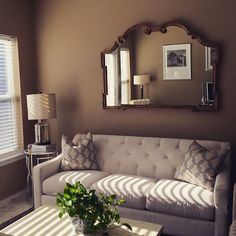 a living room with a couch, coffee table and large mirror on the wall above it