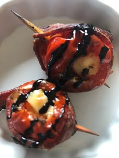 two stuffed peppers on a white plate with toothpicks