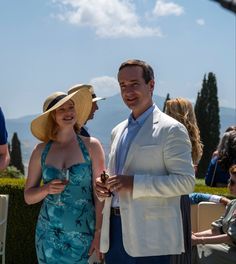 a man and woman standing next to each other in front of some people wearing hats