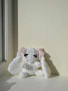 a crocheted white bunny rabbit sitting in front of a window