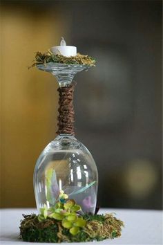 a small glass vase with moss and a candle on the top is sitting on a table