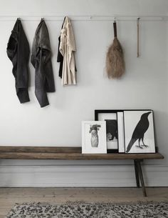 a wooden bench sitting in front of a wall with pictures and coats hanging on it