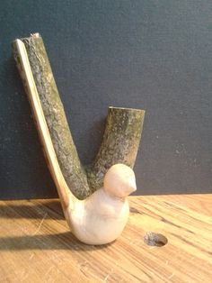 a bird figurine sitting on top of a wooden table next to a pipe