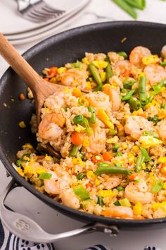 a skillet filled with shrimp, rice and vegetables